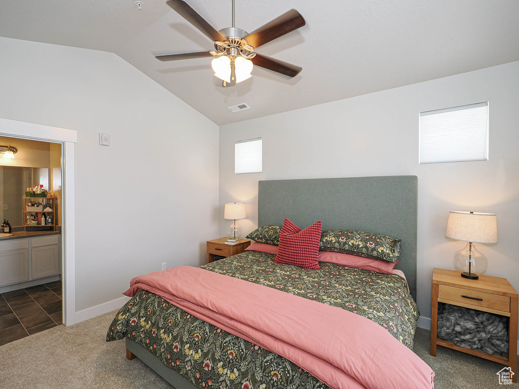 Bedroom featuring vaulted ceiling, dark colored carpet, ensuite bath, and ceiling fan