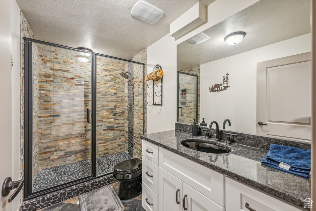 Bathroom featuring a textured ceiling, a shower stall, and vanity