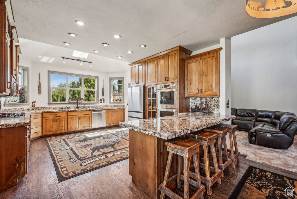 Kitchen featuring recessed lighting, a peninsula, a skylight, appliances with stainless steel finishes, and a breakfast bar area