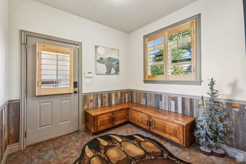 Foyer featuring a wainscoted wall, dark stone finish floors, and wooden walls