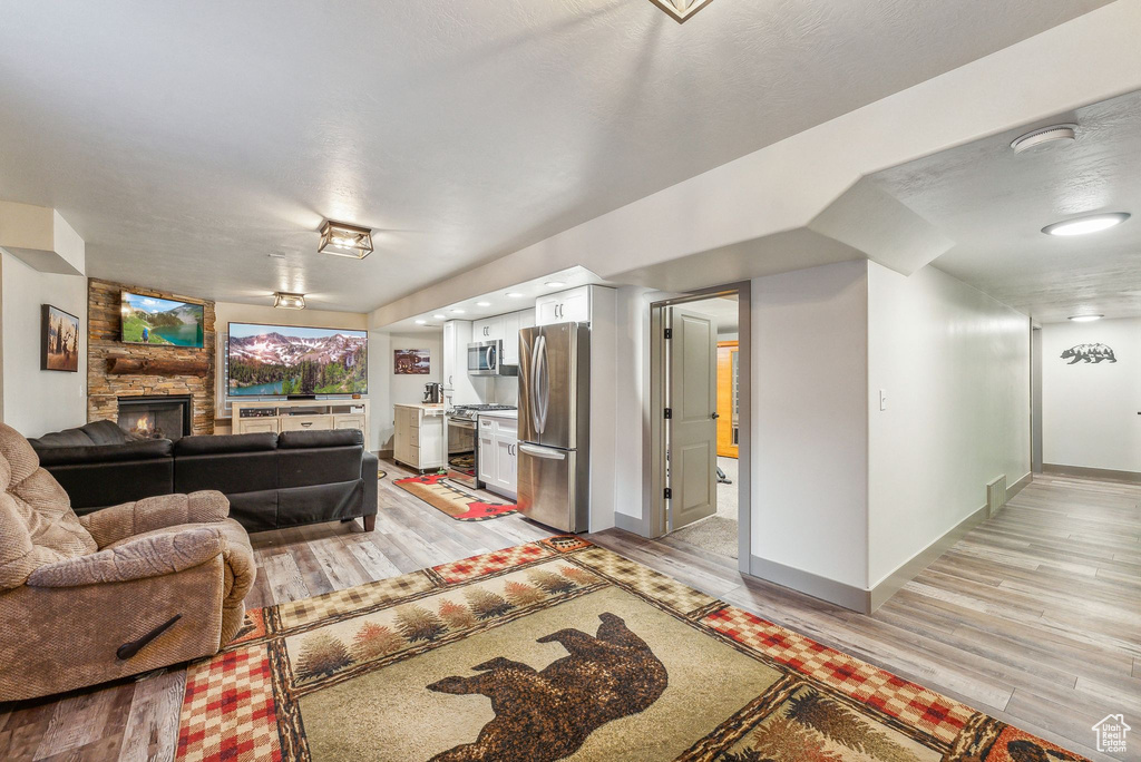 Living room featuring light wood-type flooring and a stone fireplace