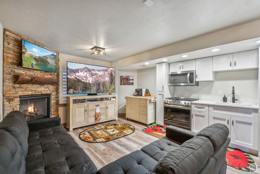Living area with light wood-style floors, a stone fireplace, and recessed lighting