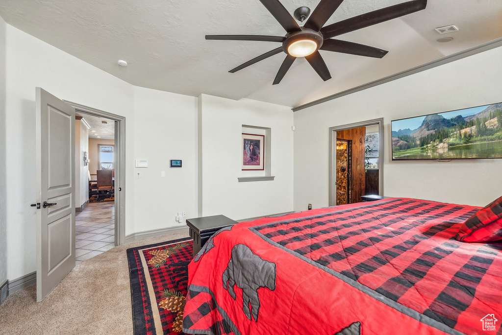 Carpeted bedroom featuring vaulted ceiling and ceiling fan