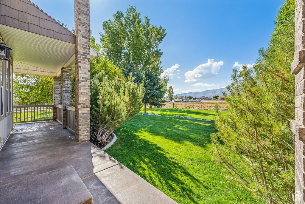 View of grassy yard with a mountain view and a porch