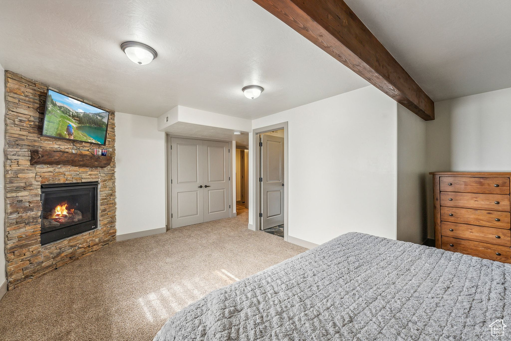 Carpeted bedroom with a fireplace and beamed ceiling