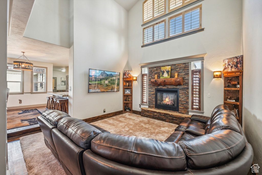 Living area featuring a stone fireplace, a towering ceiling, and wood finished floors