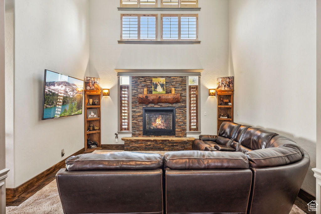 Living area featuring a towering ceiling, a fireplace, and wood finished floors