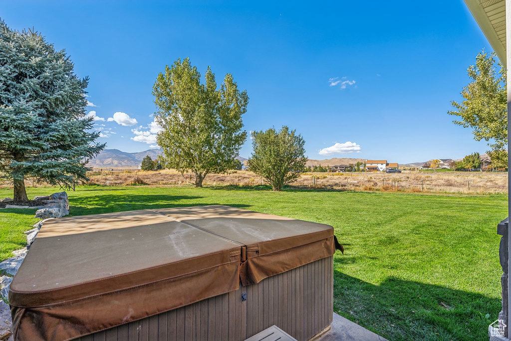 View of green lawn with a hot tub and a mountain view