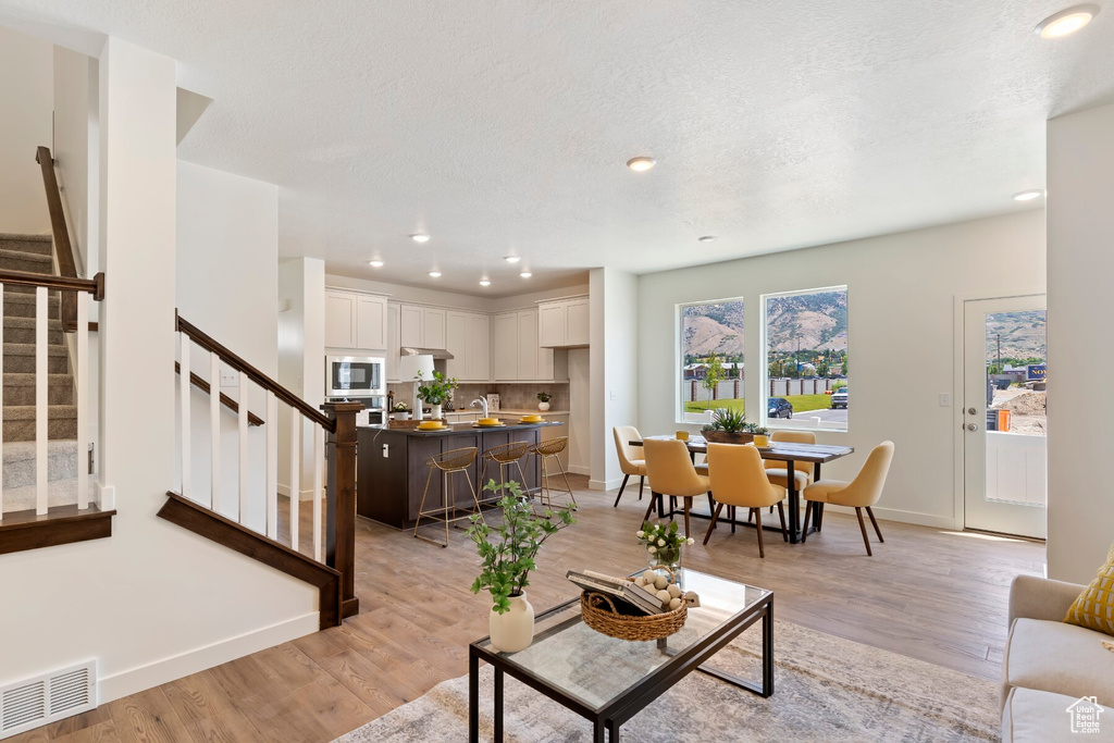 Living room with stairway, light wood finished floors, recessed lighting, and a textured ceiling