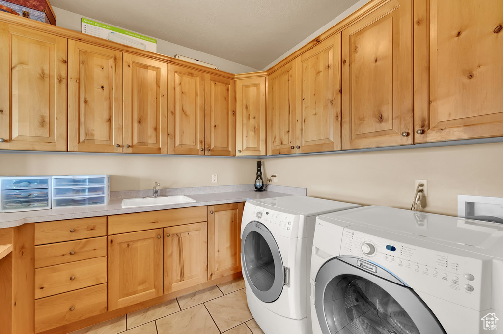 Laundry room featuring cabinet space, washing machine and dryer, and light tile patterned floors