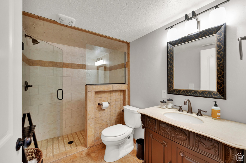 Full bathroom with a stall shower, vanity, and a textured ceiling