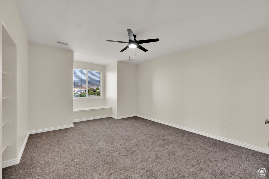 Unfurnished room featuring ceiling fan and dark carpet