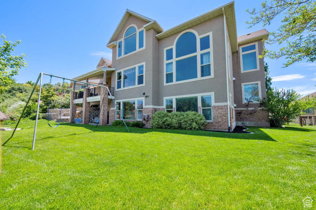 Rear view of property featuring stucco siding, brick siding, and a yard