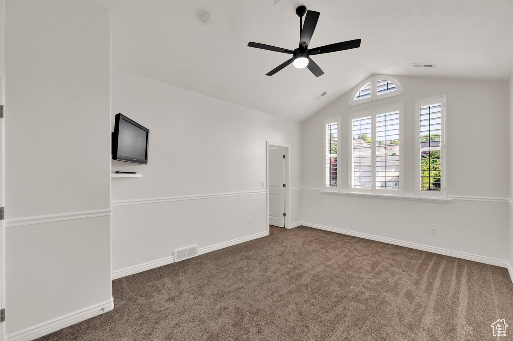 Empty room featuring ceiling fan, lofted ceiling, and carpet floors
