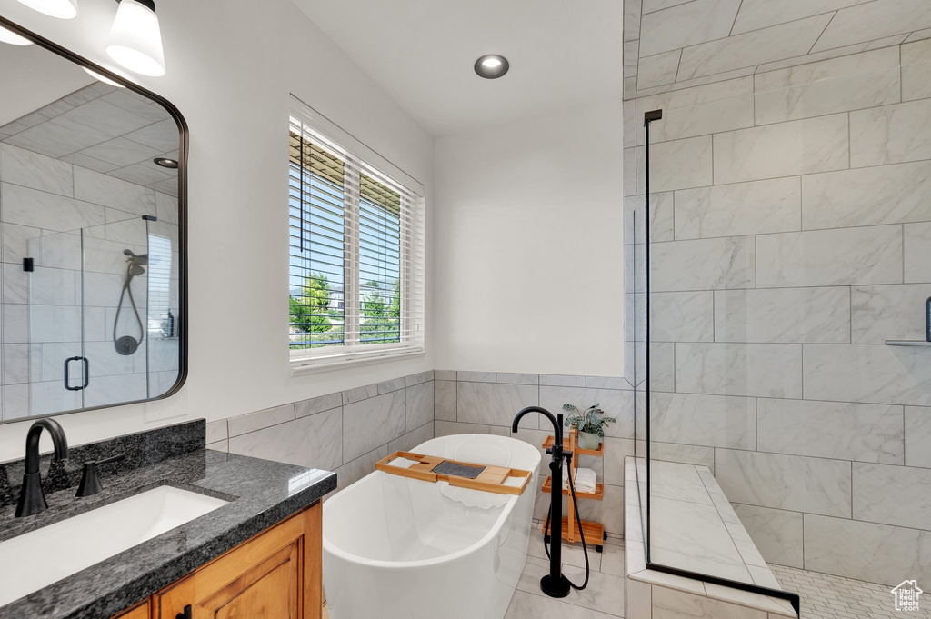 Bathroom featuring tile walls, tiled shower, vanity, a freestanding bath, and tile patterned flooring