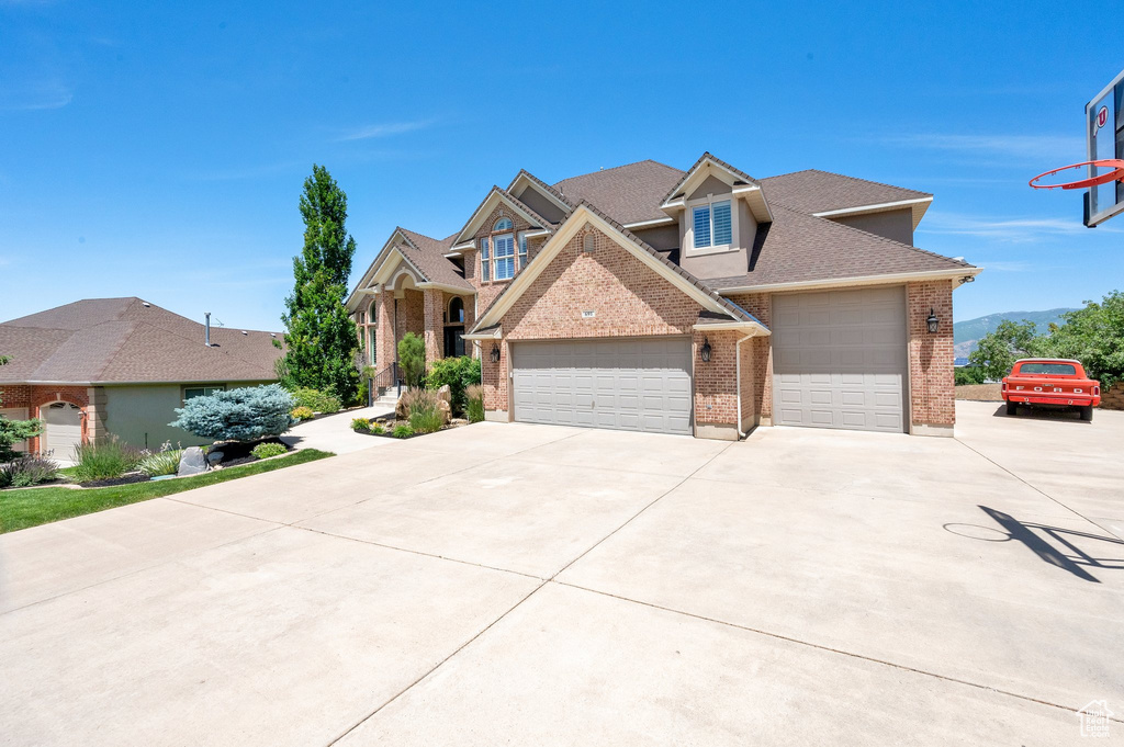 Traditional-style house with brick siding, driveway, a garage, and roof with shingles
