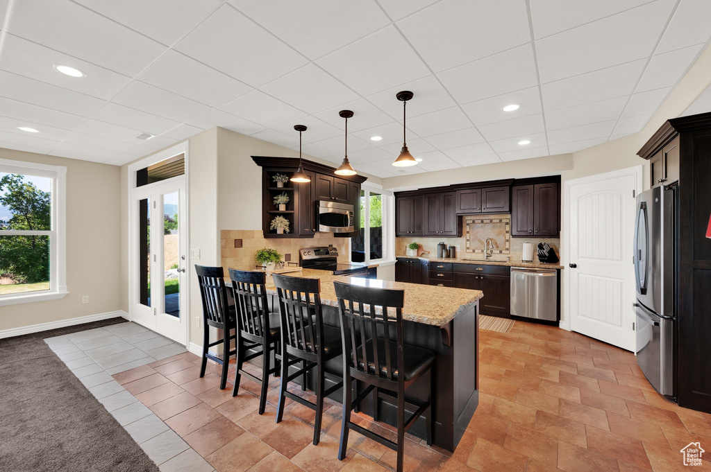 Kitchen with appliances with stainless steel finishes, a peninsula, dark brown cabinets, decorative backsplash, and open shelves
