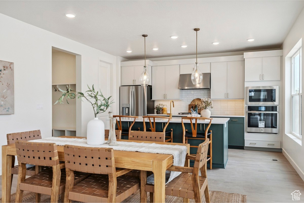 Dining area with recessed lighting and light wood-type flooring