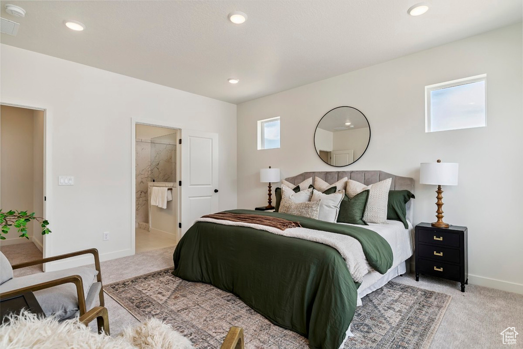 Bedroom with light colored carpet, recessed lighting, and connected bathroom
