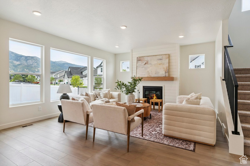 Living area featuring stairs, a mountain view, wood finished floors, a glass covered fireplace, and recessed lighting