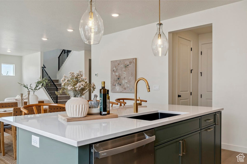 Kitchen featuring dishwasher, a center island with sink, light countertops, and recessed lighting