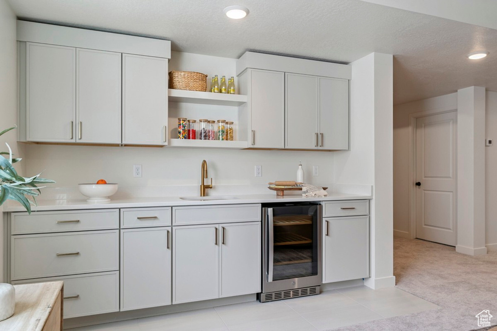Kitchen featuring light countertops, wine cooler, open shelves, light colored carpet, and recessed lighting
