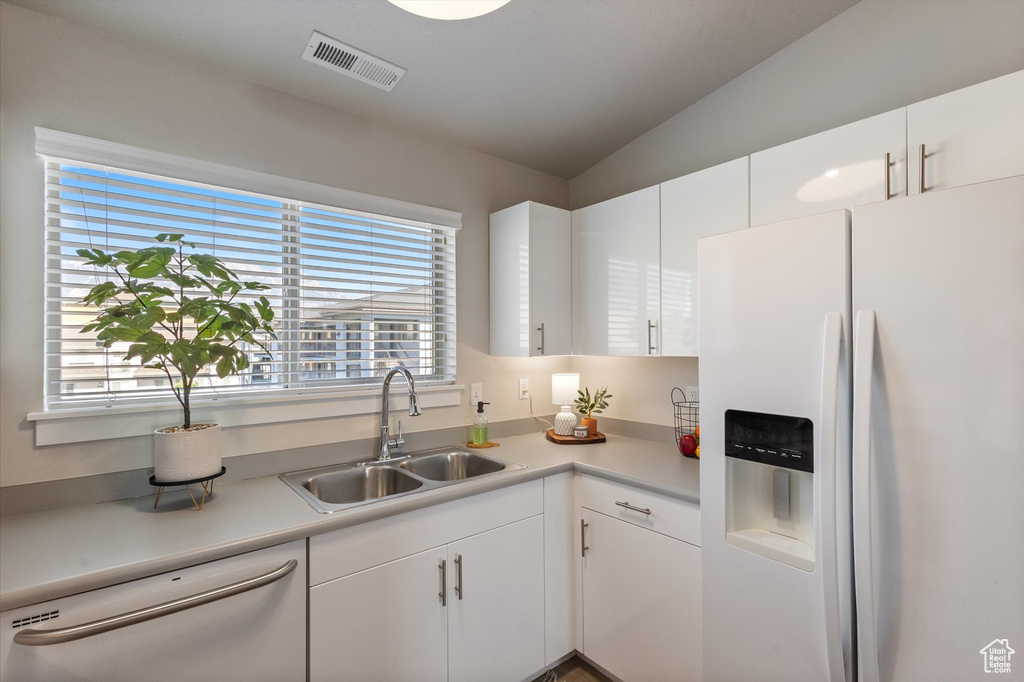 Kitchen featuring white appliances, light countertops, white cabinetry, and lofted ceiling