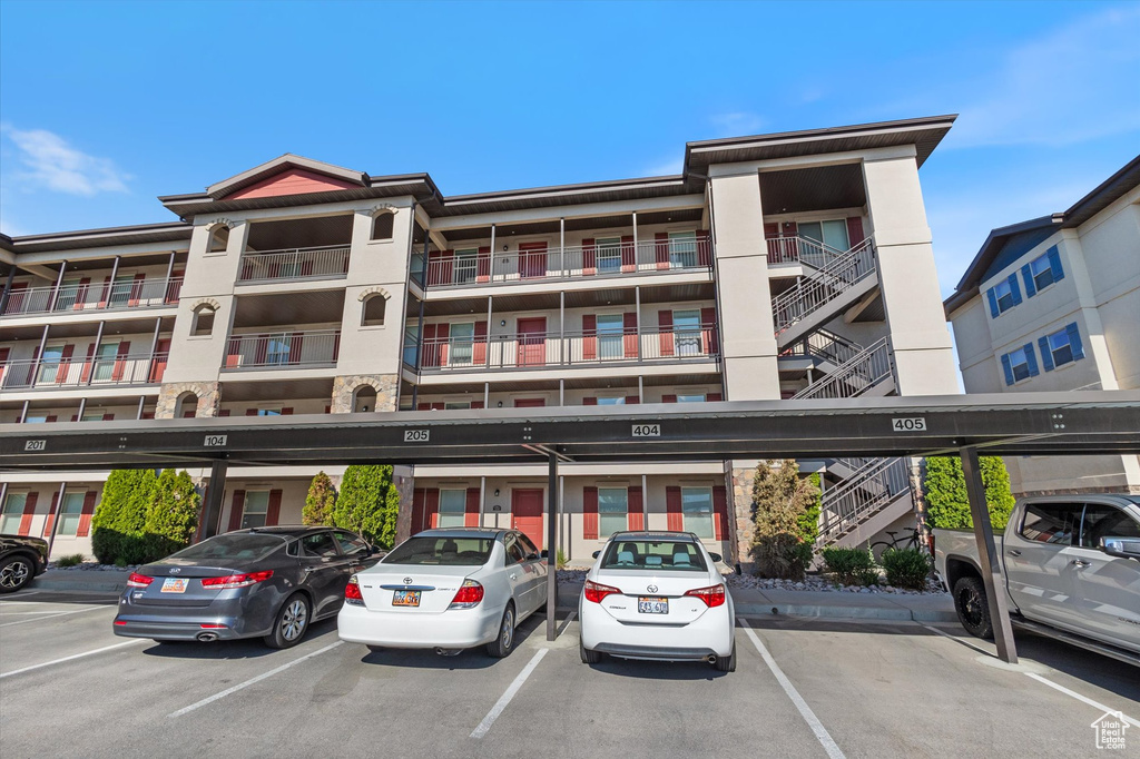 View of apartment building / complex featuring covered parking and stairs