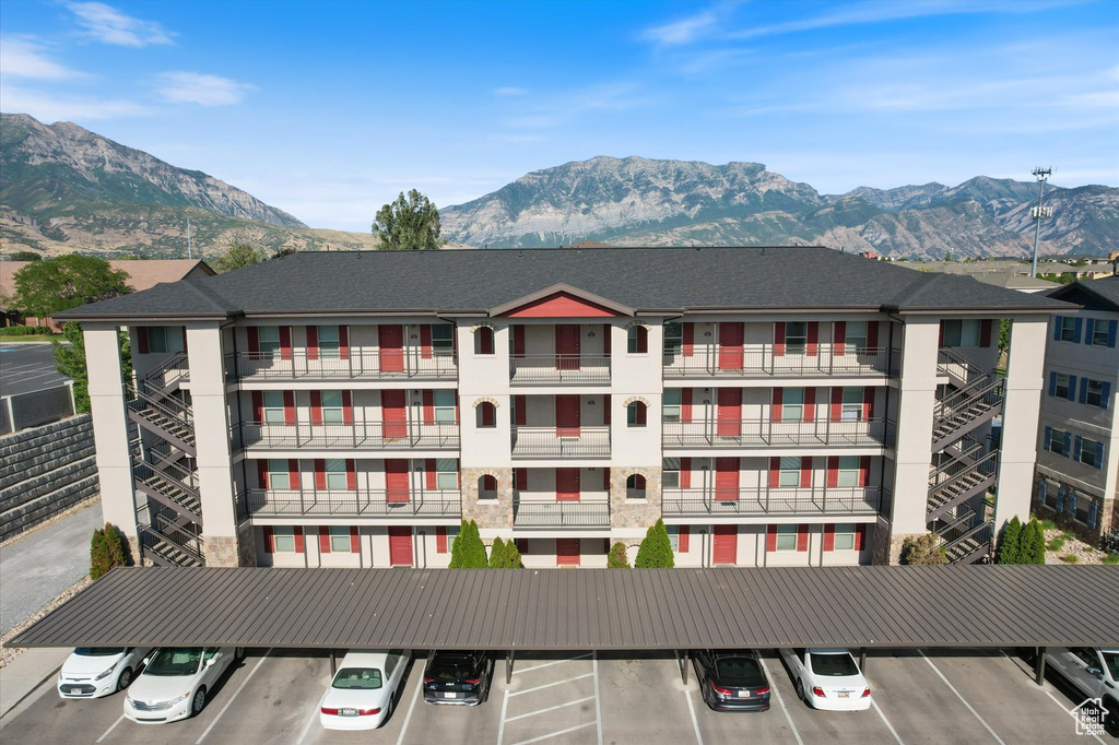 View of apartment building / complex featuring covered and uncovered parking and a mountain view