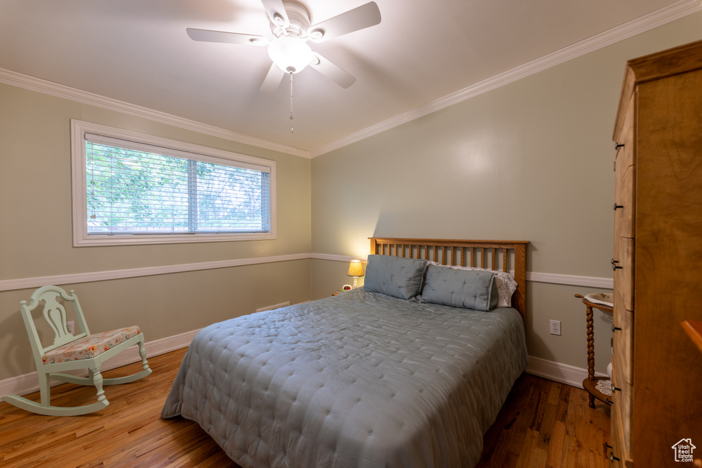 Bedroom with wood finished floors, ornamental molding, and ceiling fan