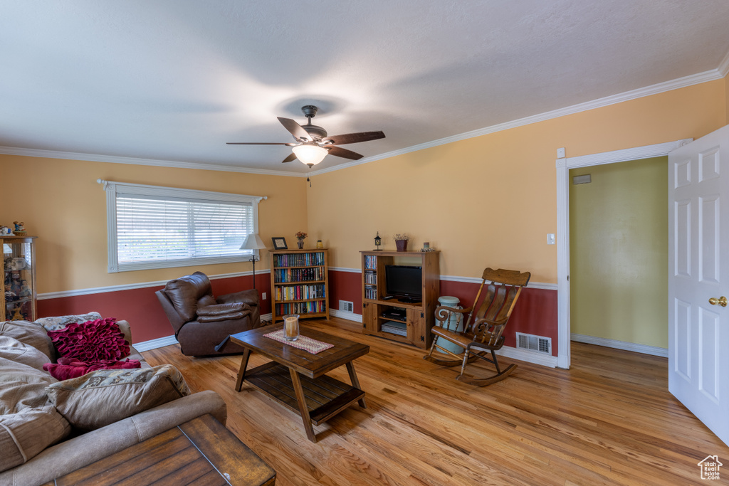 Living area featuring a ceiling fan, light wood-style flooring, and ornamental molding