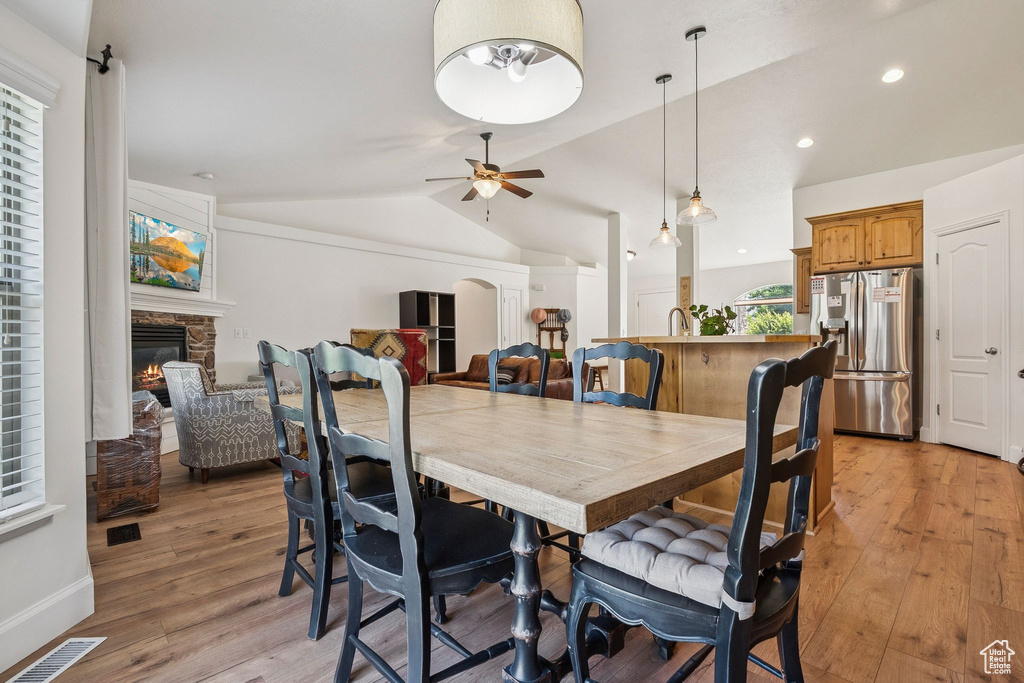 Dining room featuring a fireplace, ceiling fan, lofted ceiling, light wood-type flooring, and recessed lighting