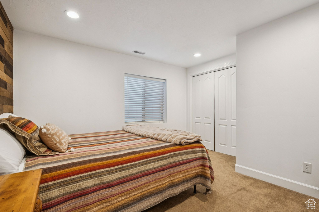 Bedroom with light colored carpet, recessed lighting, and a closet