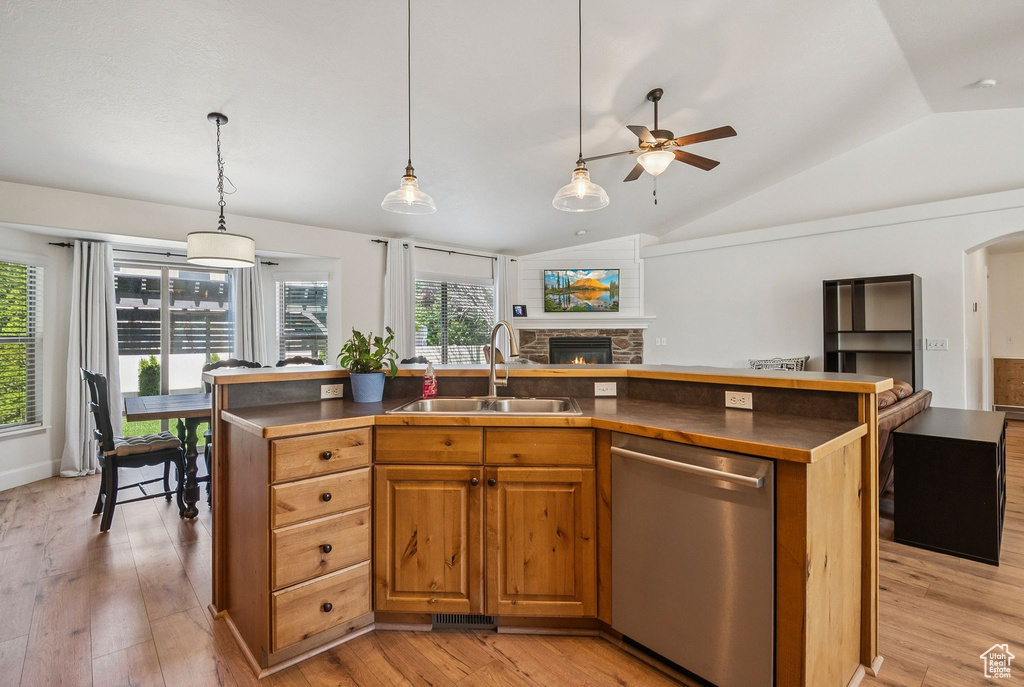 Kitchen with stainless steel dishwasher, open floor plan, vaulted ceiling, dark countertops, and a ceiling fan