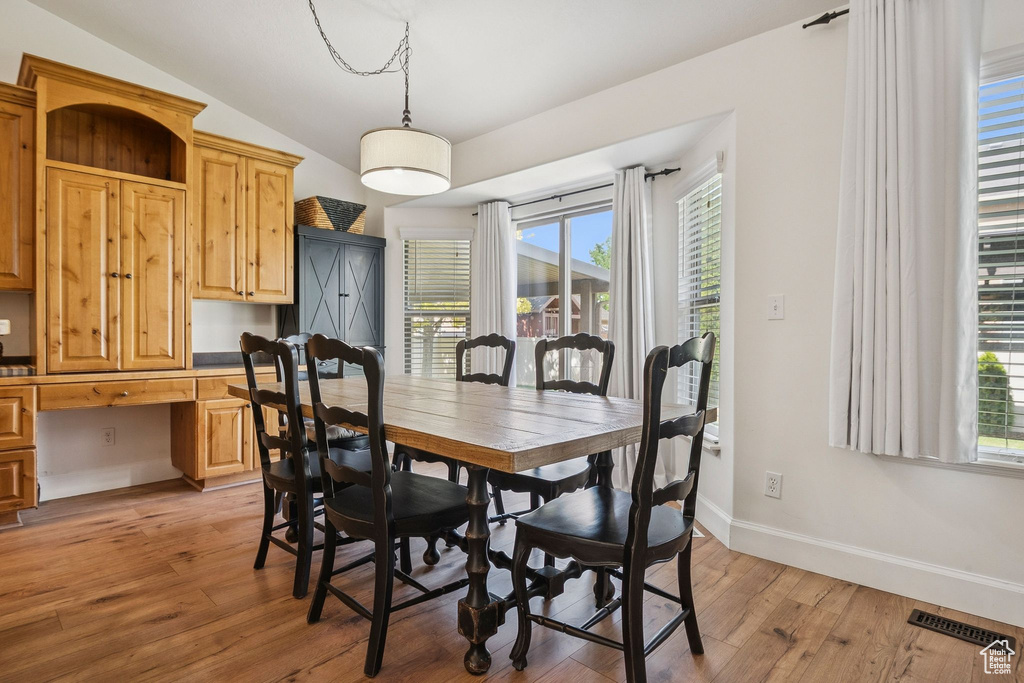 Dining space with vaulted ceiling, light wood-style floors, and built in study area