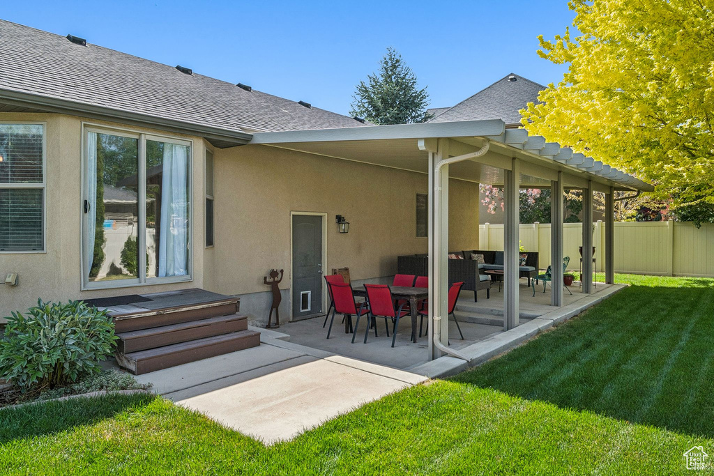 Back of house with a shingled roof, stucco siding, and a patio area
