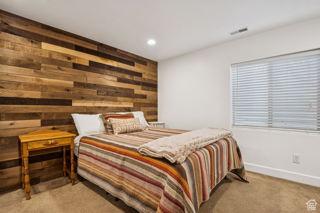 Bedroom with wooden walls, light colored carpet, and recessed lighting