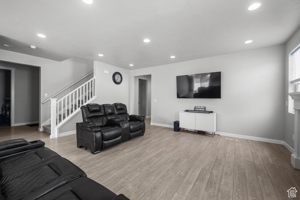 Living room featuring stairway, light wood finished floors, recessed lighting, and a fireplace