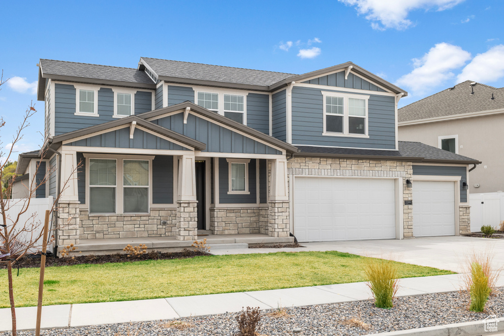 Craftsman house featuring stone siding, board and batten siding, covered porch, concrete driveway, and an attached garage