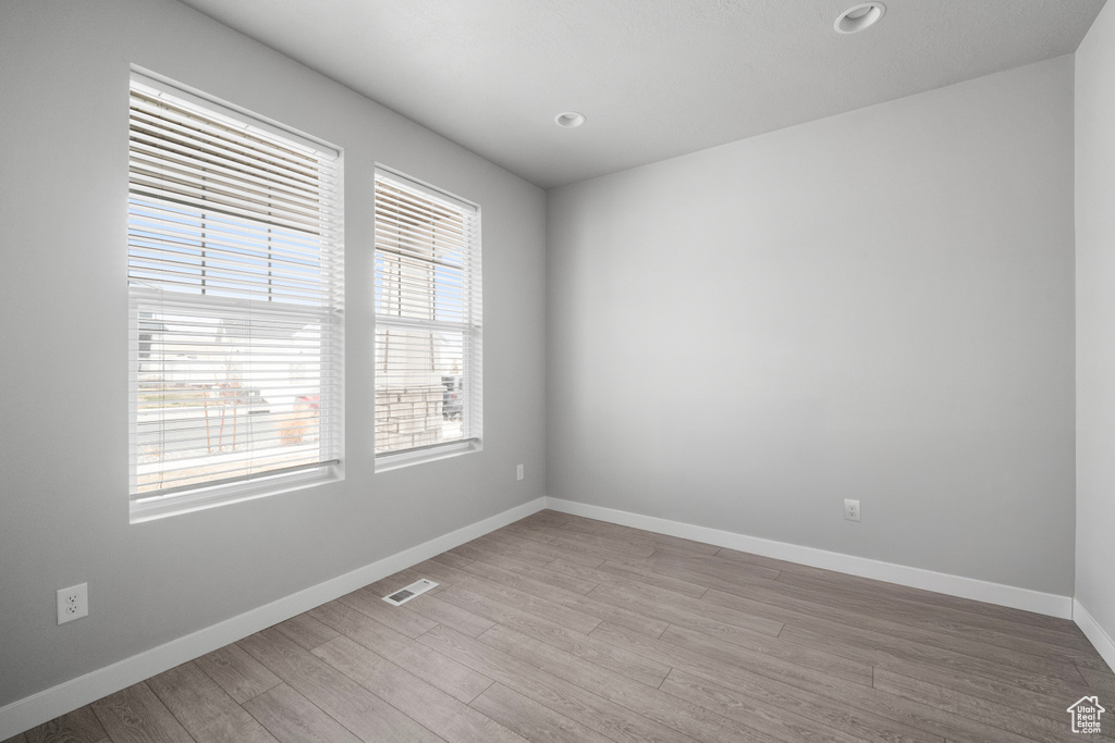 Empty room with light wood-style flooring and recessed lighting