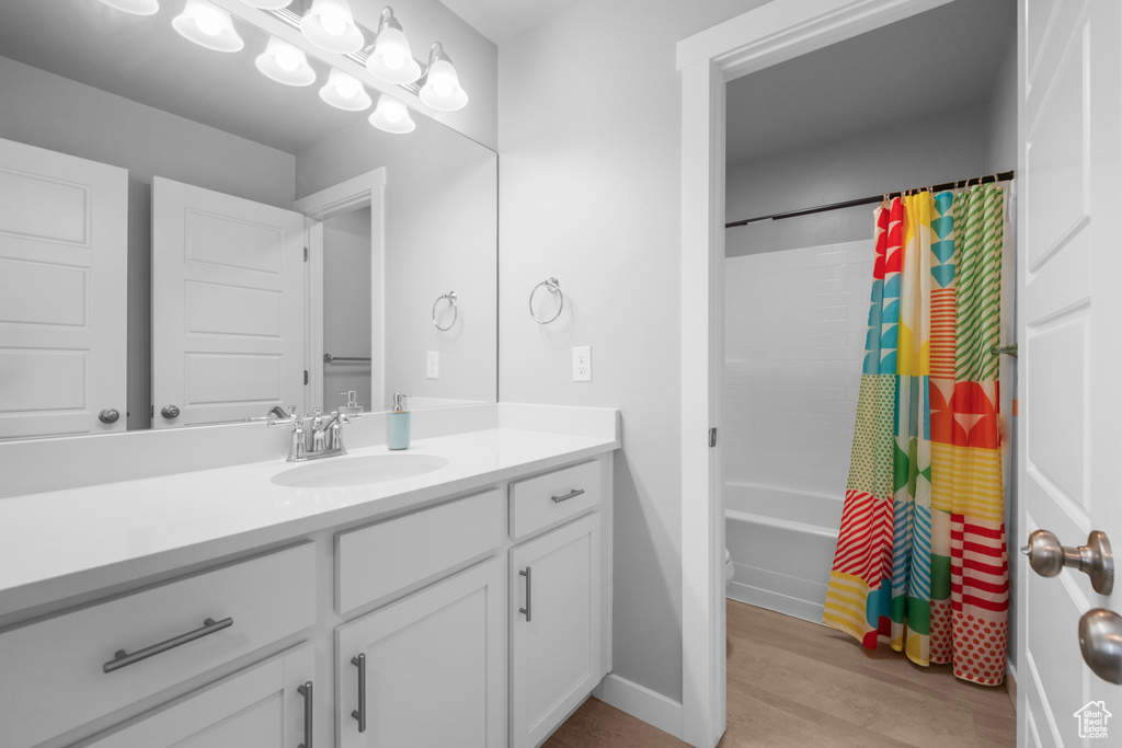 Bathroom featuring vanity, shower / bath combination with curtain, and wood finished floors