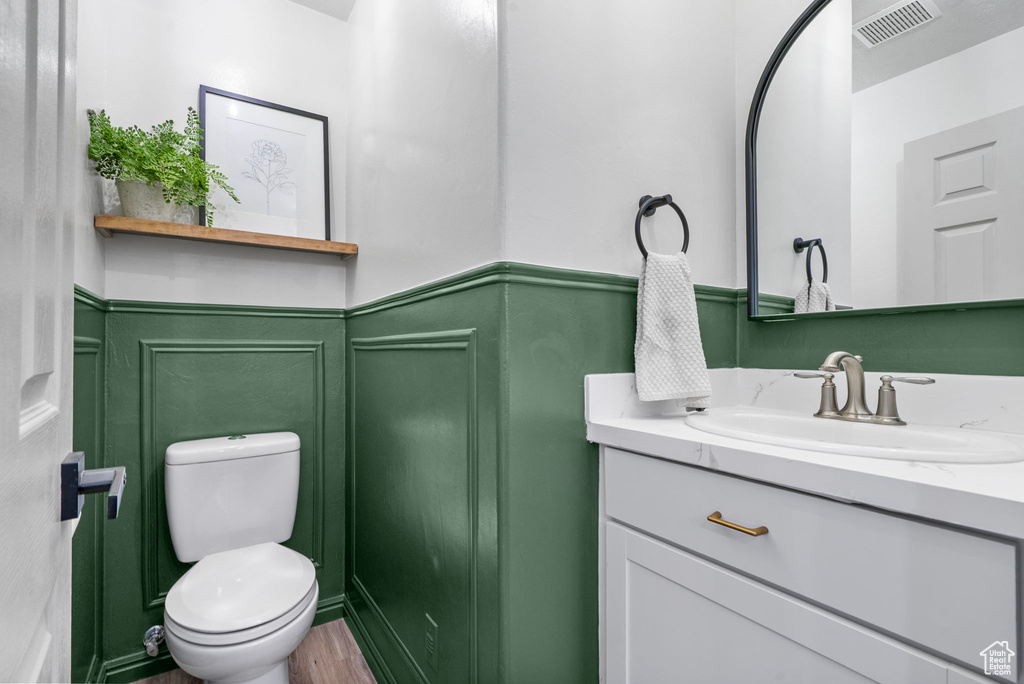 Half bath featuring vanity, a wainscoted wall, and a decorative wall