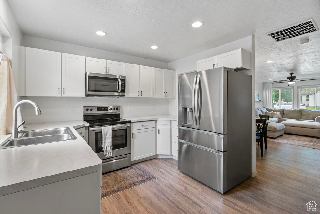Kitchen featuring appliances with stainless steel finishes, white cabinetry, light countertops, recessed lighting, and a textured ceiling