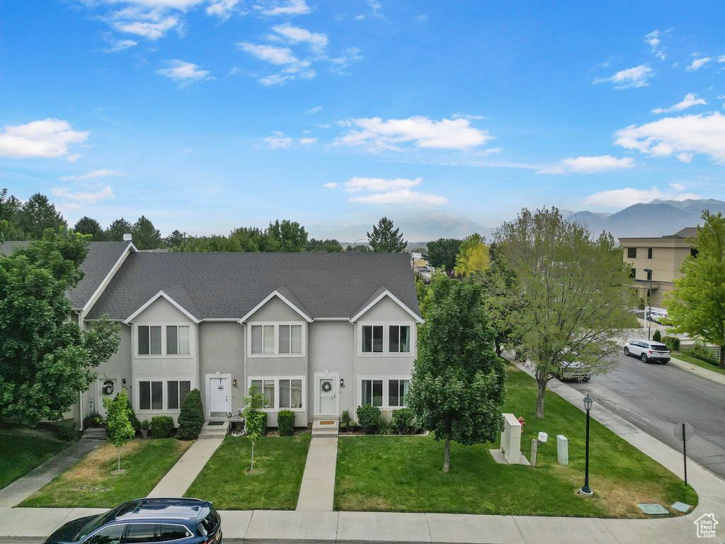 Traditional-style house featuring stucco siding, a front lawn, and a shingled roof