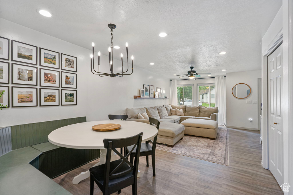Dining area featuring wood finished floors, a ceiling fan, recessed lighting, a textured ceiling, and a chandelier