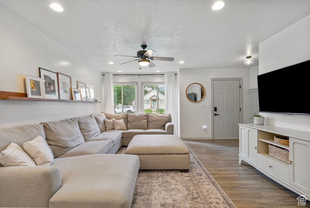 Living area featuring a ceiling fan, light wood-style flooring, recessed lighting, and a textured ceiling