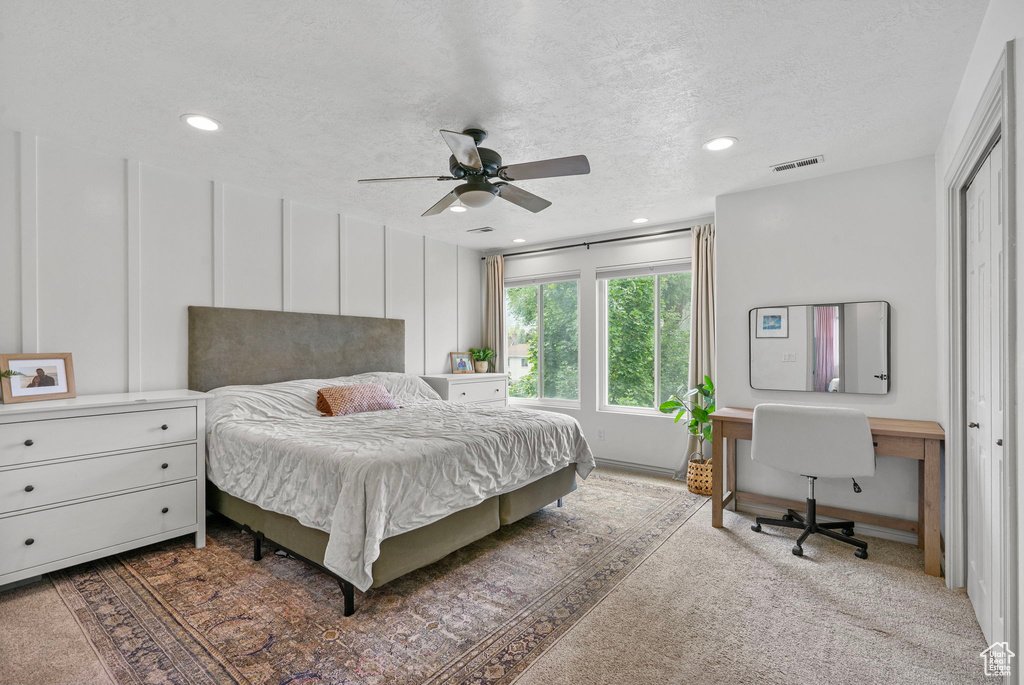 Carpeted bedroom featuring a textured ceiling, recessed lighting, and a ceiling fan