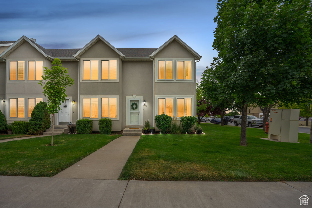 Traditional-style home with stucco siding, a lawn, and entry steps