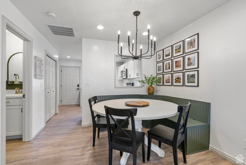 Dining room featuring light wood-type flooring, a chandelier, and recessed lighting