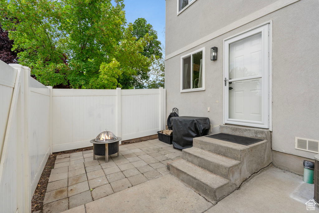 Fenced backyard with an outdoor fire pit, a patio area, and entry steps